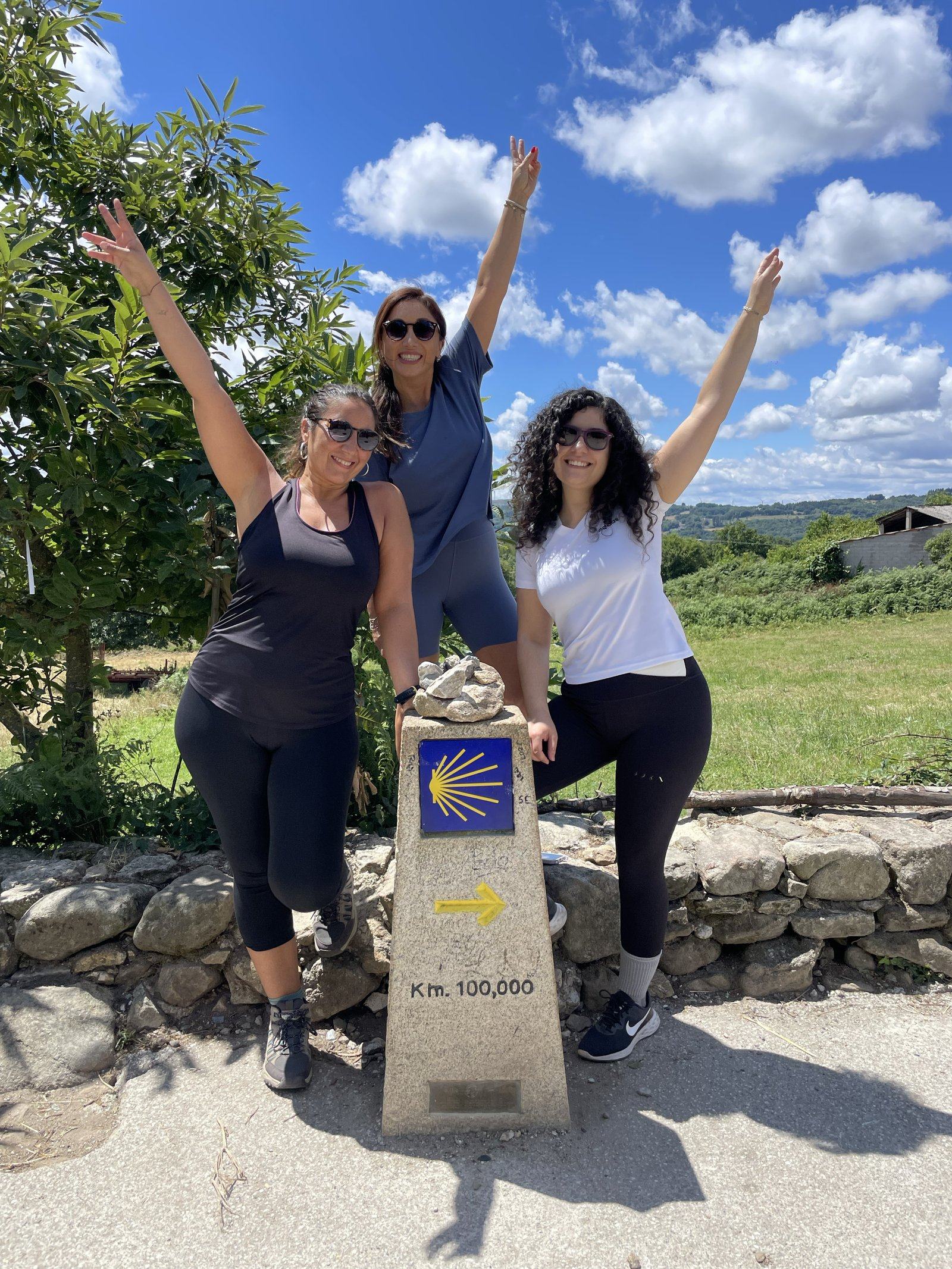 Less, Raquel y Fran sonriendo juntas en el monolito del Km. 100 del Camino Francés